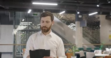 Genç, esmer, sakallı bir erkek, alışveriş merkezine gidiyor, elinde klasörle. Yakışıklı satıcı, tasarımcı etrafa bakıyor, arıyor. Kentsel yaşam tarzı kavramı.