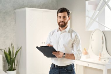 Sergi merkezinde kameraya gülümserken klipsli tabletle duran profesyonel bir perakendeciydi. Zarif erkek uzmanın portresi, arka planda yatak odası sergisi var. İş yeri kavramı.