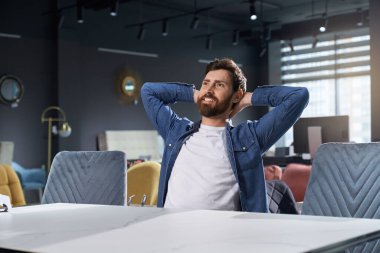 Mobilya dükkanında rahat, mutlu beyaz bir adam yeni rahat sandalyesinde oturuyor. Keyifli sakallı adamın portresi. Rahat koltukta dinlenirken mutlu ve tatmin olmuş hissediyor. Dinlenme kavramı.