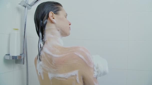 샤워를 하면서 어깨를 스펀지를 사용하는 여자의 뒷모습 — 비디오
