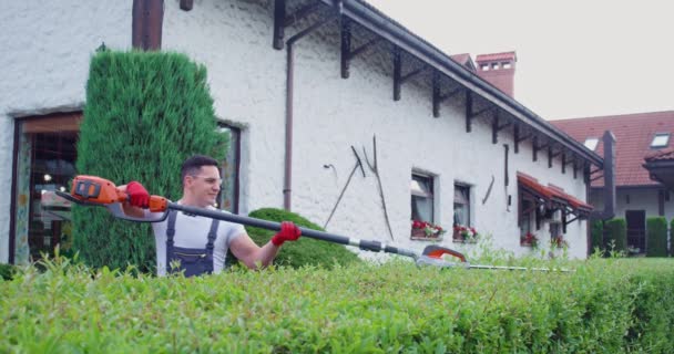 Homem Caucasiano Usando Cortador Sebes Elétrico Para Moldar Arbustos Cobertos — Vídeo de Stock