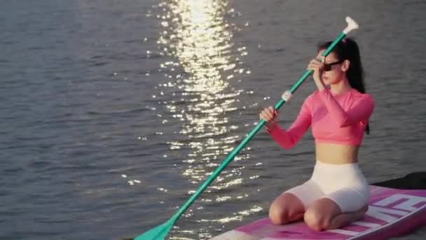 迷人的高加索女人 用长桨漂浮在城市湖上五颜六色的水底上 夏季日落在水面上的反射 — 图库视频影像