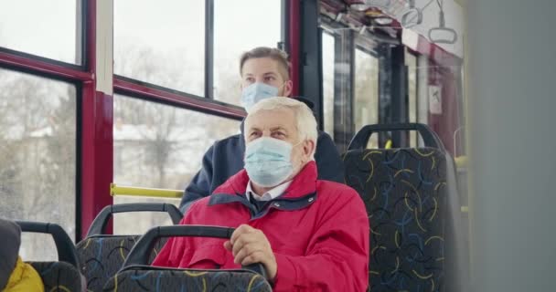 バスに座っている乗客の正面図は コロナウイルスから保護します 白髪の老人は 男の子がバスに座って マスクを着ている 隔離と世界的パンデミックの概念 — ストック動画