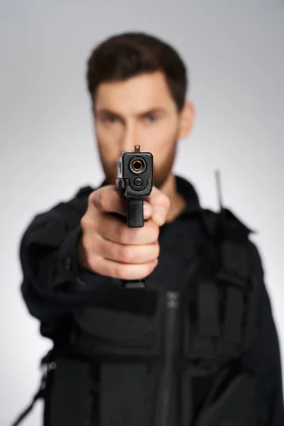 武装的高加索警察用枪对着摄像机瞄准 有选择的重点 近距离的警察手枪枪口 模糊轮廓的警察背景 武器概念 — 图库照片