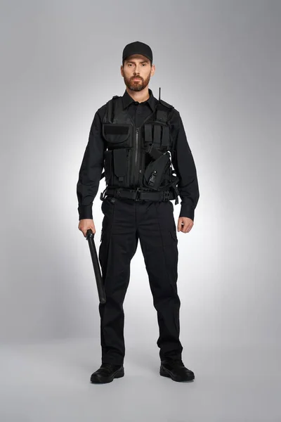 Důvěryhodný Policista Černé Uniformě Stojící Obuškem Studiu Přední Pohled Vousatého — Stock fotografie