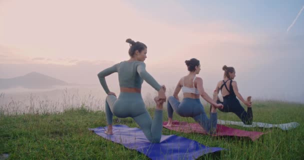 夏の山の間の夕方のトレーニング中にヨガマットに体を伸ばす3人の白人女性 柔軟性 バランス — ストック動画