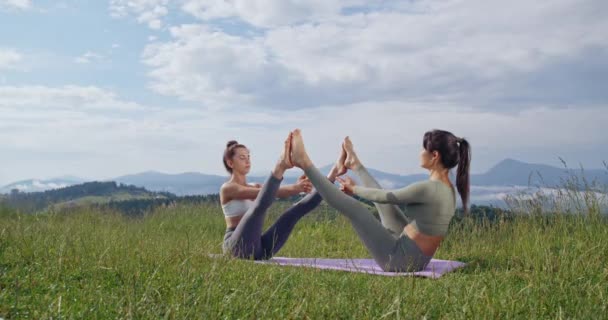 Två Motionskvinnor Som Sitter Med Utsträckta Ben Yogamattan Och Mediterar — Stockvideo