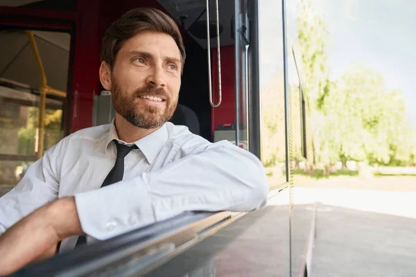 Hymyilevä Mies Istuu Kuljettajan Istuimella Toinen Käsi Levällään Avoimessa Ikkunassa — kuvapankkivalokuva