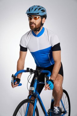 Triathlon male athlete cycle training indoors. Front view of caucasian fit cyclist wearing sports equipment, riding, isolated on white studio background. Concept of sport lifestyle, action, motion. clipart