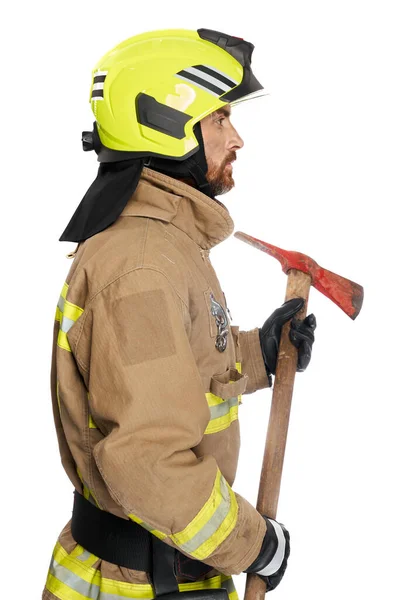 以男性消防员为重点 使用木斧工具工作 一个身穿消防制服的中年男子的侧面视图 他带着斧头 在白色的工作室背景下与外界隔绝 工具概念 — 图库照片