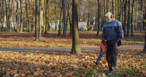 Blanke Senior Man Met Koptelefoon Handschoenen Overall Die Het Stadspark — Stockvideo