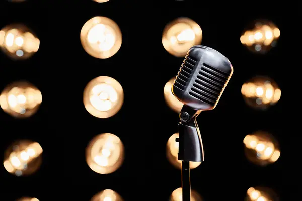 Vintage microphone podcast symbol with copy space on dark sparkling background. Close up of isolated image of retro microphone on stage with lights, blurred background. Concept of performance.