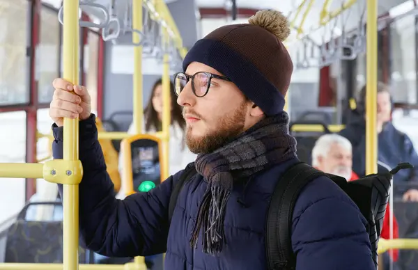 창문을 바라보는 배낭이있는 안경으로 펜시브 남성의 움직이는 버스에 남자와 승객의 로열티 프리 스톡 사진