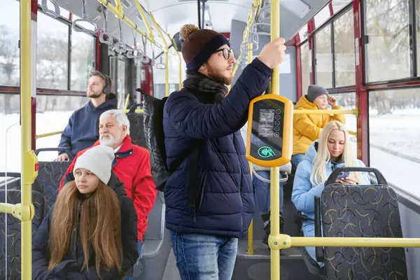 公共交通機関の後ろに座っている窓や乗客を見ているバックパック付きのメガネの大人の男性の側面のビュー 完全に移動するバスで停止するのを待っている若者の作物 都市生活の概念 ストック写真
