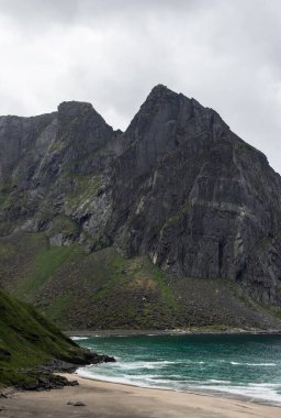 Yaz güneşi dağlarda parlıyor ve Kvalvika Sahili, Lofoten, Norveç 'in turkuaz okyanusu