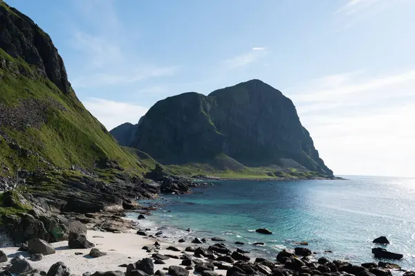 stock image A rocky, white sand beach and a sea cliff and rock formation on a sunny day in Norway's Lofoten archipelago