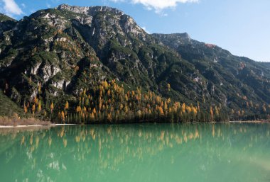 Güneşli sonbahar dağ manzarası Lago di Landro 'ya yansıyor