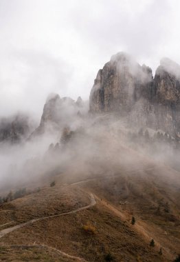 Dağ sisinin içinden kayalık bir dağ manzarasına giden bir yürüyüş yolu.