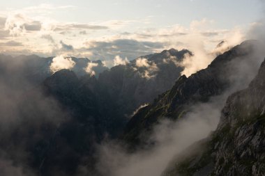 Slovenya 'nın destansı manzarası Julian bir yaz akşamında alkış tutuyor. Akşam ışığında dik dağlık vadileri sis kaplıyor..
