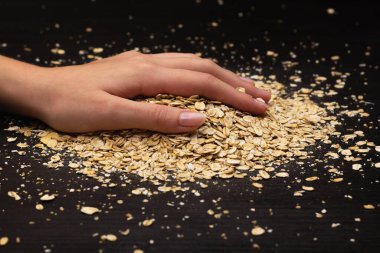 Kadın elleri siyah arka plana müsli döküyor.