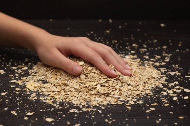 Kadın elleri siyah arka plana müsli döküyor.
