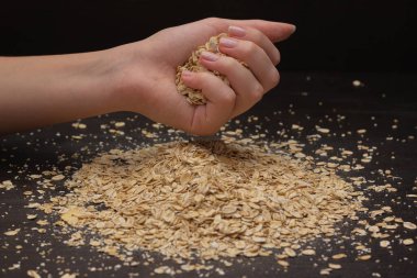Kadın elleri siyah arka plana müsli döküyor.