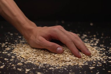 Erkek eller siyah arka plana müsli döküyor.