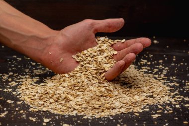 Erkek eller siyah arka plana müsli döküyor.