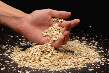 Erkek eller siyah arka plana müsli döküyor.