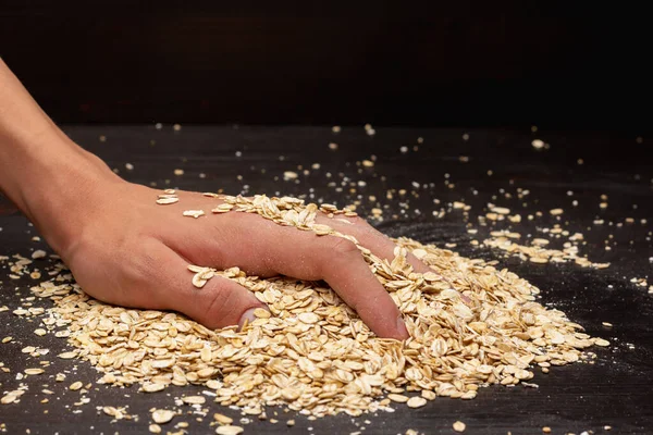 Erkek eller siyah arka plana müsli döküyor.