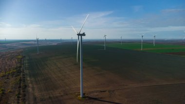Rüzgâr türbinleri insansız hava aracının bakış açısından sahada duruyor.