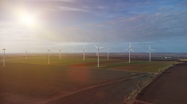 Rüzgâr türbinleri gün batımında İHA 'nın bakış açısından tarlada duruyor.