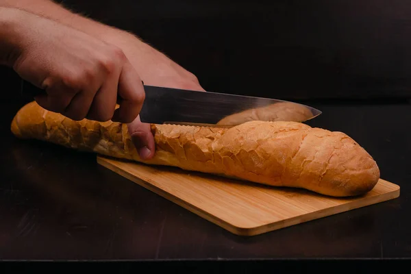Männliche Hände Schneiden Brot Auf Einem Schneidebrett Auf Einem Holzhintergrund — Stockfoto