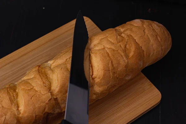 白面包和一把刀躺在木制底板上 — 图库照片