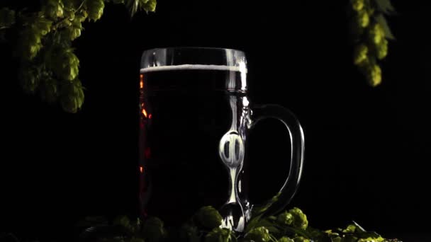 ブラックライトは ホップのある木の背景にフルビールグラスでダウン遷移します — ストック動画