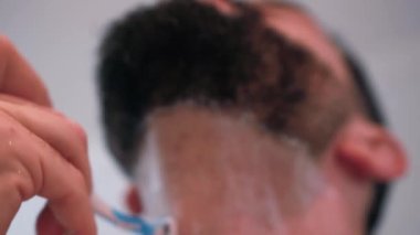 Banyoda tıraş olan bir adam işe hazırlanıyor.