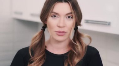 Kameraya bakan çekingen bir kadının kapalı mekan portresi. Saçları örgülü esmer kız duygularını kontrol altında tutuyor.