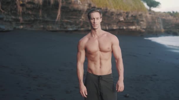 运动后的白种人赤身裸体在海滨散步 年轻运动员带着弹性带走在沙滩上的湿沙滩上的前景 男人的美的概念 高质量的4K镜头 — 图库视频影像