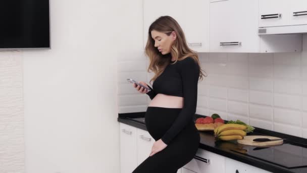 Mutfakta Akıllı Telefonuyla Gülümseyen Hamile Bir Kadın Gelecekteki Anne Internette — Stok video