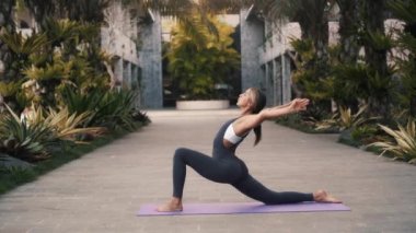 Genç, formda bir kadın dışarıda hilal hareketi yapıyor. Yoga aktivitesi denge, esneklik ve stres atımı için iyidir.
