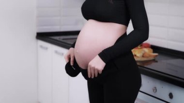 Üçüncü üç aylık dönemde hamile bir kadının karnını doyurmak ve sırt ağrısını azaltmak için karın bandı taktığı bir yüz resmi yok. Müstakbel anne karnına dokunup okşayarak bebeğine olan sevgisini ifade ediyor.