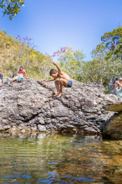 Brezilyalılar, 2025 Temmuz 'unda Brezilya' nın Cavalcante şehrinde güzel bir nehre atlayan çocukları izlerken eğleniyorlar..