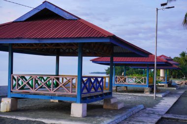 Nuhon Endonezya 'da yer alan plajda kırmızı çatıları olan mavi çardaklar.