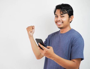 Yakışıklı, gülümseyen ya da mutlu Asyalı genç adam donanma tişörtü giymiş, elinde akıllı telefonlar olan, izole edilmiş beyaz arka planda sohbet eden..