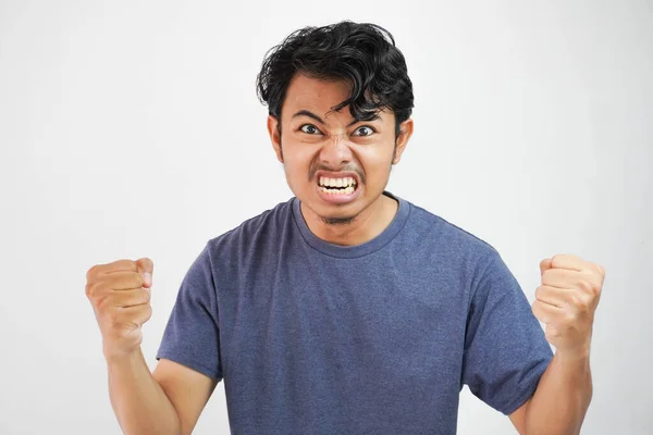 stock image Angry aggressive young asian man wearing t shirt navy color shouting out loud with ferocious expression and mad raising fists frustrated