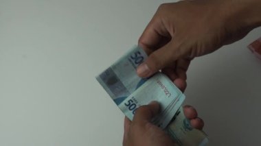 50 bin rupia 'lık banknotlar sayan bir adam. Beyaz bir arka planda Endonezya parası.