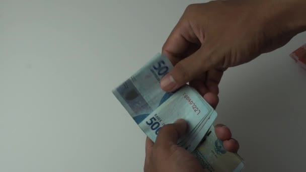 男の手は5万ルピア紙幣を数え白い背景にインドネシアのお金 — ストック動画