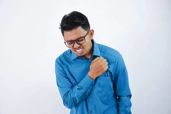 Asian young man with glasses holding his chest in chest pain or coronary heart disease wearing blue shirt isolated on white background