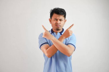 Düşünceli genç Asyalı bir adamın portresi. Kolları çapraz. Parmakları havada, beyaz arka planda mavi tişört giyiyor.