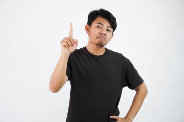 amazed or proud young asian man wearing black t shirt standing point finger up isolated on white background